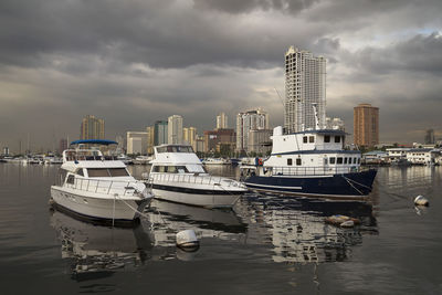 Boats moored in harbor against buildings in city