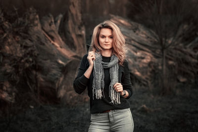 Portrait of young woman standing against trees