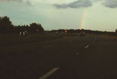 Silhouette of dog on road against sky