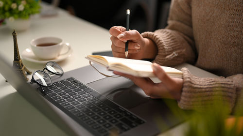 Midsection of woman using laptop on table