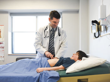 Doctor examining abdomen of child on an exam table of a clinic.