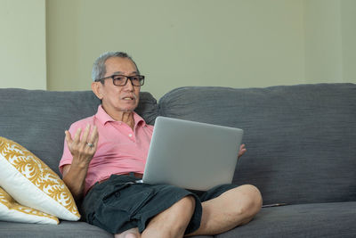 Young man using mobile phone while sitting on sofa at home