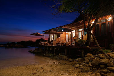 Luxury resort by stone arch and sea against twilight sky at dusk in ko man klang, rayong, thailand.