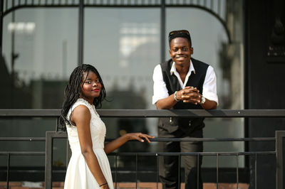 Portrait of young woman and boy standing by railing outdoors