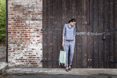 Full length of man standing against brick wall