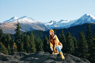 Rear view of woman sitting on mountain against sky