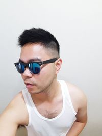 Young man wearing sunglasses against wall