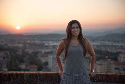 Portrait of young woman standing against sky during sunset