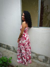 Woman standing against pink wall