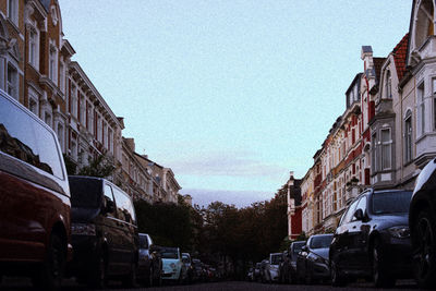 Cars on street by buildings against sky