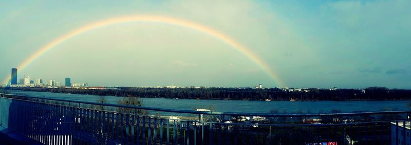 Scenic view of rainbow over river in city