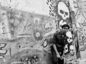 Portrait of smiling young man standing against graffiti wall