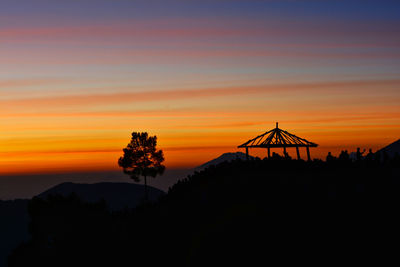 Silhouette plants on land against romantic sky at sunset