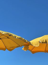 Low angle view of parasol against clear blue sky