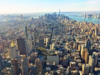 Aerial view of city buildings by sea against sky