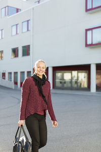 Portrait of happy teenage girl with shoulder bag on high school campus