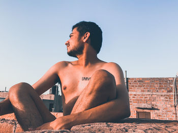 Young man looking at camera against clear sky