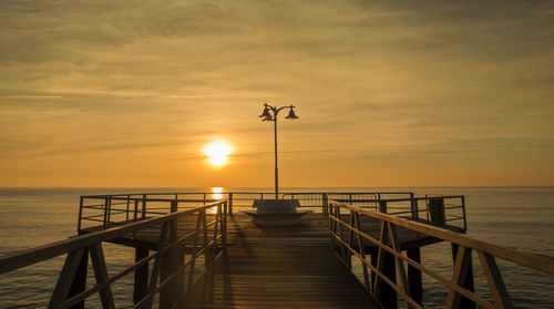 Pier over sea against sky during sunset