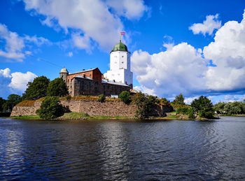 Building by river against cloudy sky