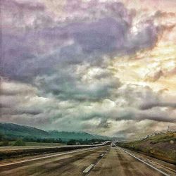 Road passing through landscape against cloudy sky