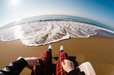 Low section of woman on shore at beach against sky