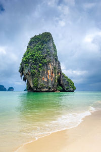 Rock formation on beach against sky