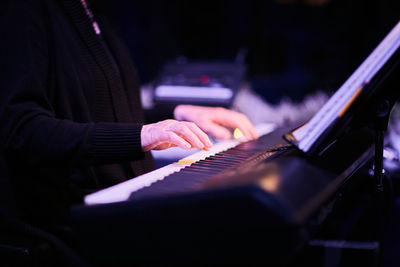 Cropped wrinkled hands of musician playing piano