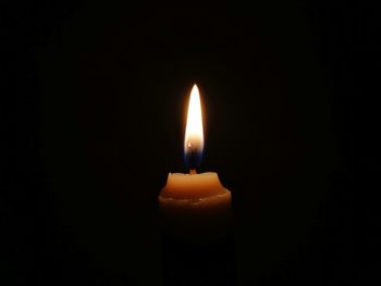 Close-up of lit candle in darkroom