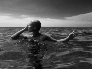 Woman swimming in sea against sky