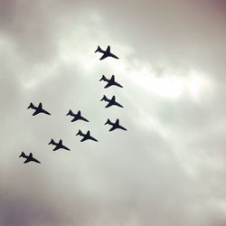 Low angle view of silhouette airplanes flying against sky