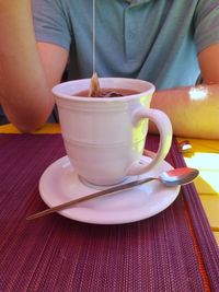 Close-up of hand holding drink sitting on table