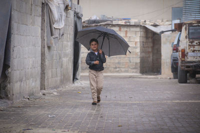 Little refugee children with umbrella in the rain, refugee with umbrella.