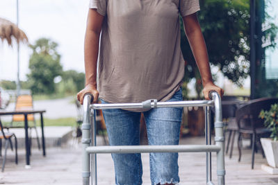 Rear view of woman with bicycle standing on railing