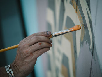 Cropped hand of painter painting wall