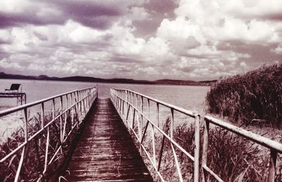 Bridge over river against cloudy sky