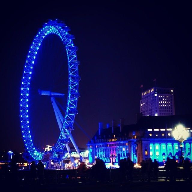 illuminated, night, arts culture and entertainment, architecture, built structure, building exterior, ferris wheel, city, amusement park ride, amusement park, long exposure, clear sky, travel destinations, sky, city life, modern, multi colored, famous place, lighting equipment, low angle view