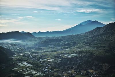 Aerial view of townscape and mountains against sky