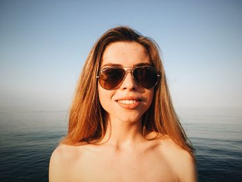 Portrait of sensuous young model in black swimwear standing against sea