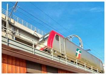 Low angle view of train on bridge against blue sky