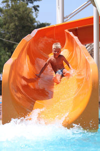 Full length portrait of boy sitting on slide