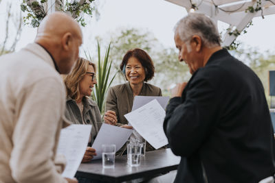 Smiling male and female senior friends reading menu card at restaurant