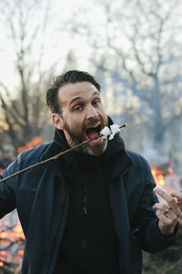 Mid adult man eating marshmallows on stick