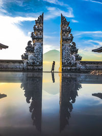 Reflection of man standing in lake at sunset