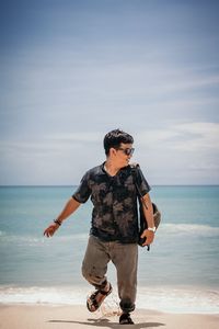 Full length of man standing on beach against sky