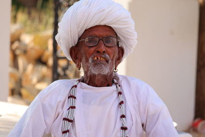 Portrait of a old aged man with his white big round cap and silver color chain , indian culture.