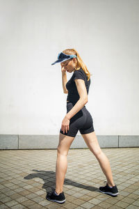 Female athlete prepares legs for cardio workout, outdoor exercise in city.