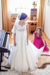 High angle view of woman assisting bride getting dressed at home