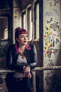 Thoughtful young woman leaning on railing in old building