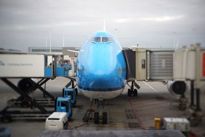 Airplane at airport runway against sky