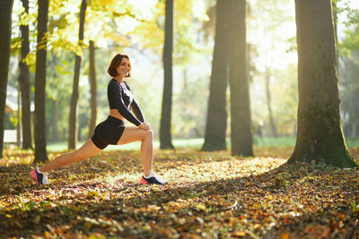 Full length of woman with arms raised in forest